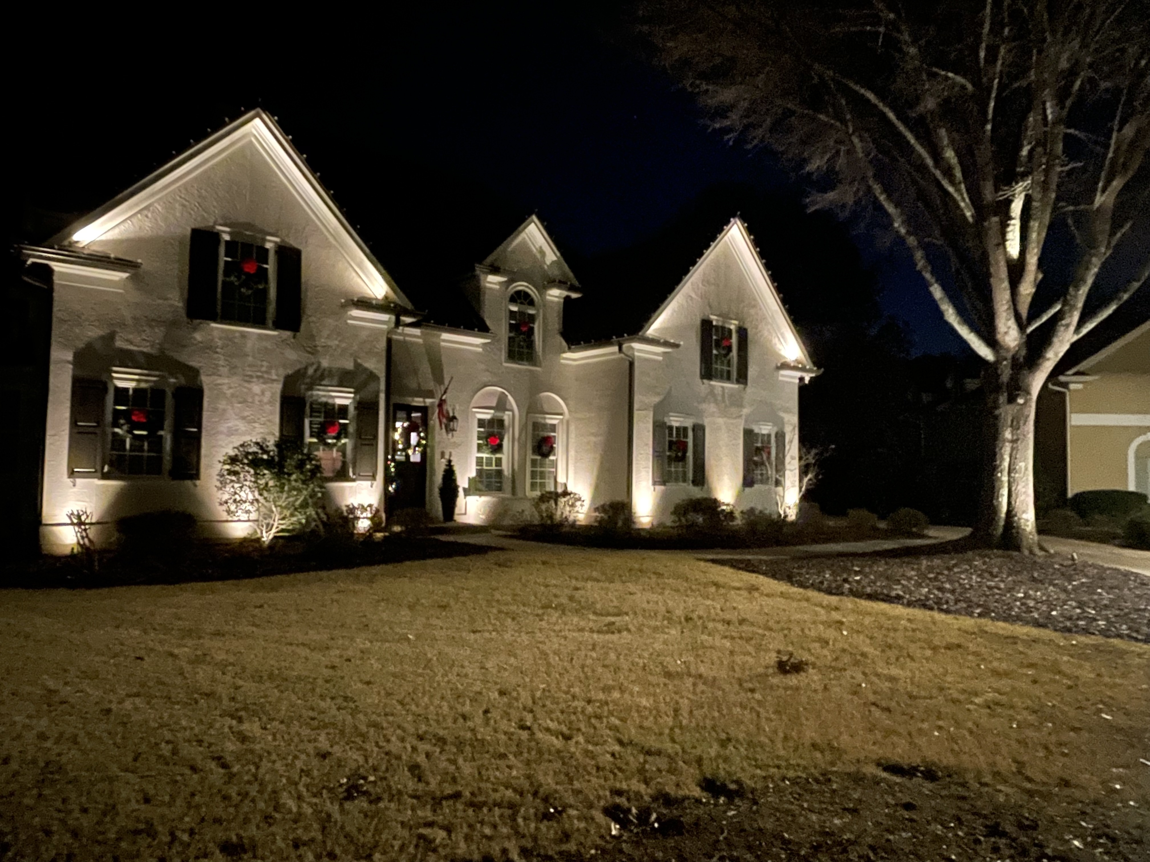 Residential exterior lighting — white home with architectural uplighting